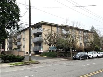 Seattle apartment for rent - A grey building with a parking lot in front.