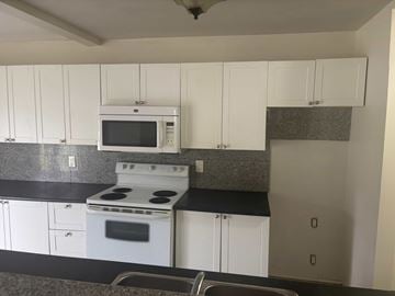 Brockville apartment for rent - A kitchen with white cabinets and a black countertop.