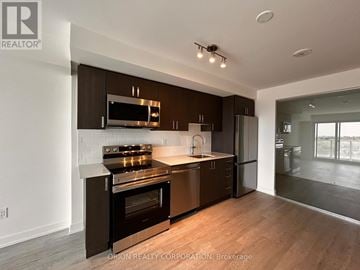 Pickering (Bay Ridges) condo for rent - A modern kitchen with dark brown cabinets and stainless steel appliances.