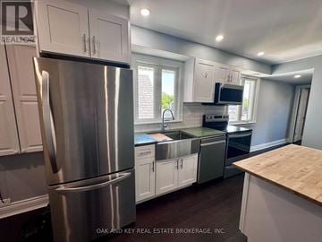 Toronto (Rockcliffe-Smythe) duplex for rent - A kitchen with a stainless steel refrigerator and white cabinets.