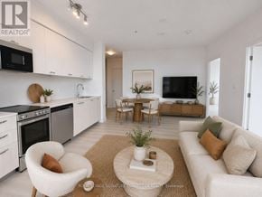 Hamilton (Corktown) condo for rent - A modern living room with a white sofa, a coffee table, and a kitchen area in the background.