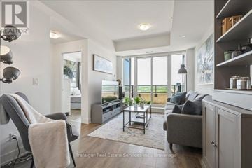 Oakville (Ro River Oaks) condo for rent - A well-lit living room with a grey sofa and a grey armchair.