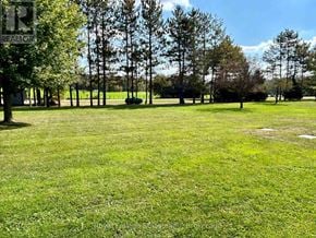 West Grey apartment for rent - A grassy field with trees in the background and a sign on the left.