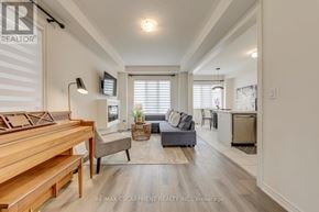 Hamilton (Waterdown) apartment for rent - A well-lit living room with a piano and a grey sofa.