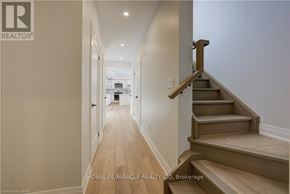 Kitchener duplex for rent - A hallway with wooden floors and a staircase with wooden steps and railings.