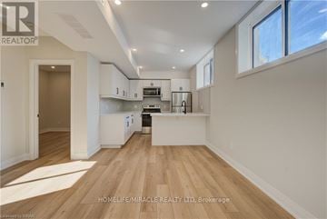 Kitchener duplex for rent - A spacious kitchen with white cabinets and a wooden floor.