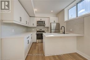 Kitchener duplex for rent - A modern kitchen with white cabinets and a wooden floor.