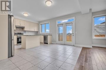 Vaughan (Kleinburg) apartment for rent - A spacious kitchen with a refrigerator, oven, and a dining table with chairs.