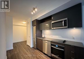 Toronto (Church-Yonge Corridor) condo for rent - A modern kitchen with dark wood cabinets and stainless steel appliances.