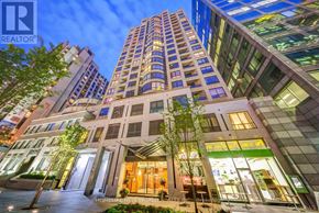 Toronto (Church-Yonge Corridor) condo for rent - A tall building with a glass facade is illuminated at night.