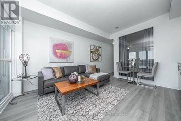 Toronto (Mimico) condo for rent - A modern living room with a grey sofa and a wooden coffee table.