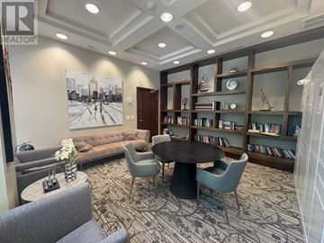 Mississauga (City Centre) condo for rent - A living room with a large painting on the wall and a bookshelf filled with books.