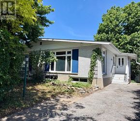 Ottawa apartment for rent - A house with a white exterior and a grey roof is surrounded by greenery.