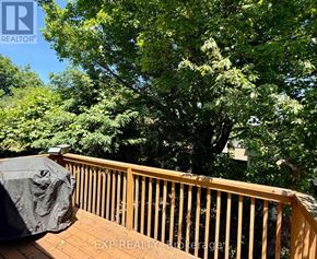 Ottawa apartment for rent - A wooden deck with a black cover and trees in the background.