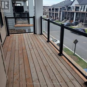 Ottawa townhouse for rent - A balcony with a wooden floor and black railings overlooks a street.