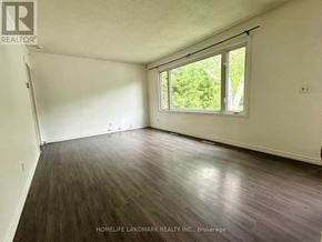 Oshawa (Vanier) apartment for rent - A room with wooden flooring and a window overlooking trees.
