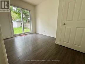 Oshawa (Vanier) apartment for rent - A room with a white door and a window with a view of a green lawn and a white fence.