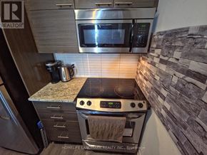 Toronto (Henry Farm) condo for rent - A modern kitchen with a stove top oven and microwave above it.