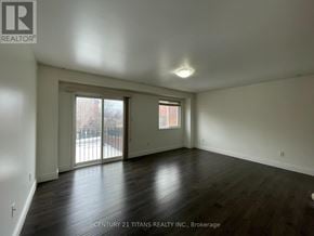 Toronto (Clairlea-Birchmount) townhouse for rent - A spacious room with wooden floors and a large window overlooking a cityscape.