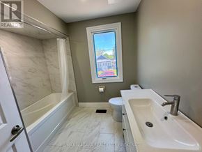 St. Catharines (Burleigh Hill) apartment for rent - A bathroom with a marble tub surround, toilet, and sink.