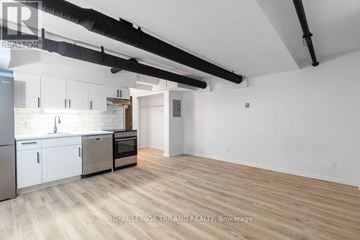 London East (East K) multi-family for rent - A spacious kitchen with white cabinets and a wooden floor.