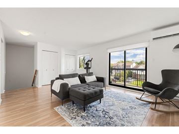 Gatineau (Gatineau) condo for rent - A living room with a grey sofa and a black chair.