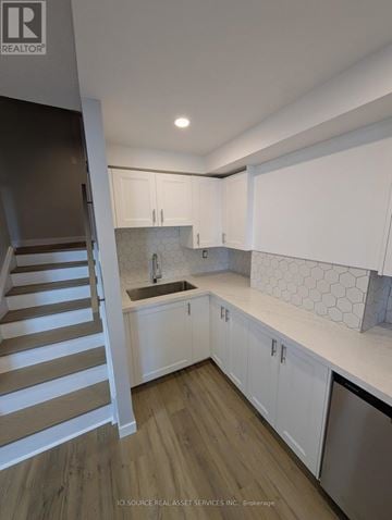 Toronto (Markland Wood) condo for rent - A kitchen with white cabinets and a wooden staircase.
