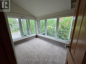 Orangeville duplex for rent - A sunny room with a carpet floor and a view of trees outside.