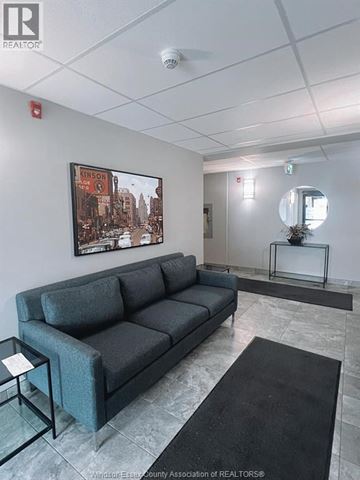 Windsor condo for rent - A living room with a grey couch and a poster on the wall.