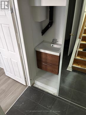 Toronto (East End-Danforth) apartment for rent - A small white bathroom with a wooden cabinet and a white door.