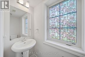 Ottawa townhouse for rent - A bathroom with a sink, mirror, and a stained glass window.
