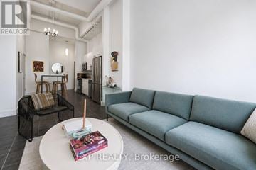 Ottawa condo for rent - A living room with a grey couch and a coffee table with a book and a candle on it.