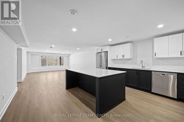 Brockville apartment for rent - A modern kitchen with white cabinets and a black island.