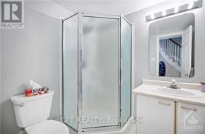 Ottawa townhouse for rent - A white toilet sits next to a glass shower stall in a bathroom.