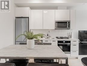 Toronto (Kensington-Chinatown) condo for rent - A modern kitchen with a marble table and white cabinets.