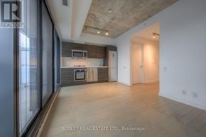 Toronto (Waterfront Communities) condo for rent - A modern kitchen with a wooden floor and a ceiling with exposed beams.