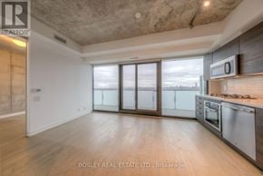 Toronto (Waterfront Communities) condo for rent - A spacious kitchen with a stainless steel refrigerator and microwave, and a large window with a view of the city.