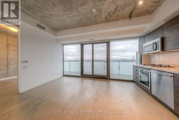 Toronto (Waterfront Communities) condo for rent - A spacious kitchen with a stainless steel refrigerator and microwave, and a large window with a view of the city.