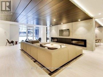 Toronto (Regent Park) condo for rent - A modern living room with a large sectional sofa and a fireplace.