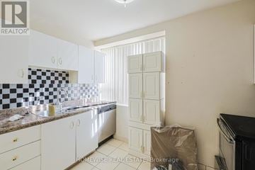 Toronto (The Beaches) multi-family for rent - A kitchen with white cabinets and a checkered backsplash.