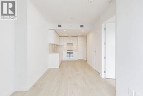 Burnaby apartment for rent - A spacious, empty room with a kitchen area in the background.