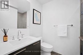 Toronto (Church-Yonge Corridor) condo for rent - A bathroom with a white toilet, a sink with a bottle of scent, and a picture on the wall.