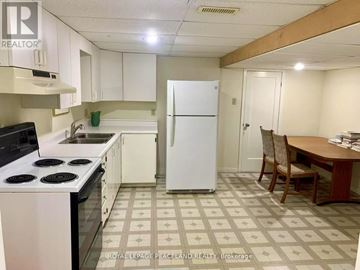 Whitchurch-Stouffville apartment for rent - A kitchen with a white fridge, black stove, and a table with chairs.