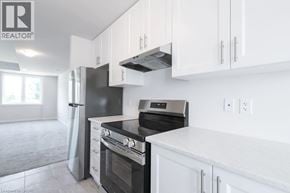 Brantford townhouse for rent - A modern kitchen with white cabinets and black appliances.