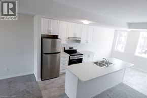 Brantford townhouse for rent - A modern kitchen with white cabinets and a stainless steel refrigerator.