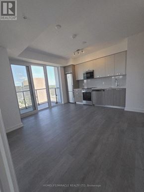 Hamilton (Corktown) condo for rent - A spacious living room with a kitchen area in the background.
