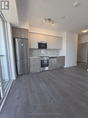 Hamilton (Corktown) condo for rent - A spacious kitchen with stainless steel appliances and a flat-screen TV mounted above the cabinets.