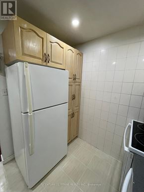 Toronto (Morningside) townhouse for rent - A white refrigerator in a kitchen with wooden cabinets.