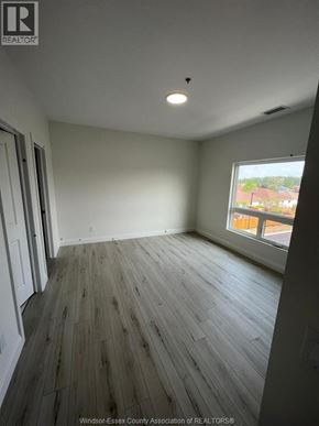 Windsor condo for rent - A room with wooden flooring and a window overlooking a residential area.