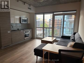 Toronto (Kensington-Chinatown) condo for rent - A modern living room with a kitchen area in the background.